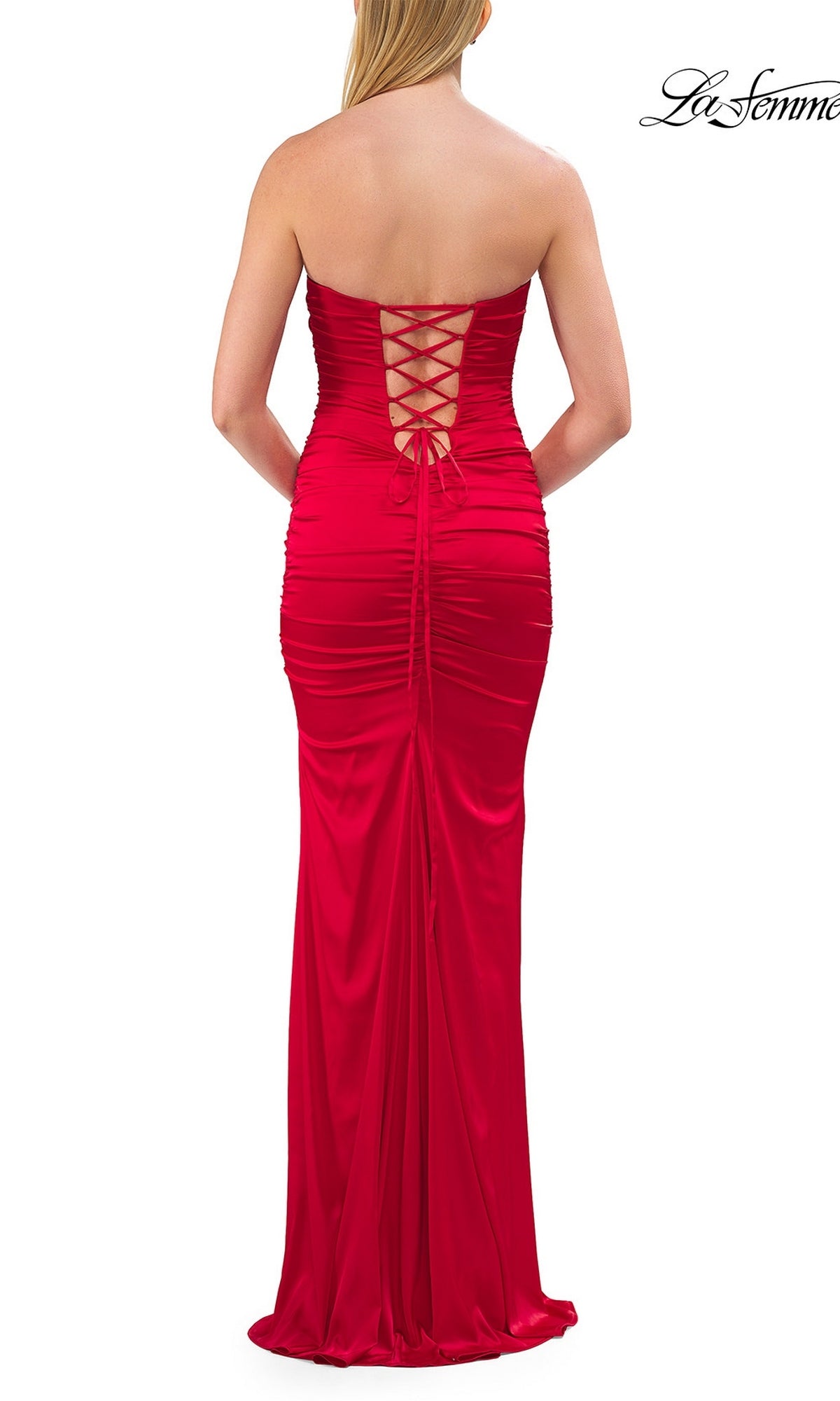 A woman stands facing away from the camera in the La Femme 33654 Lace-Up Strapless Long Prom Dress—a striking, floor-length red gown featuring a lace-up back and elegant ruched detailing.